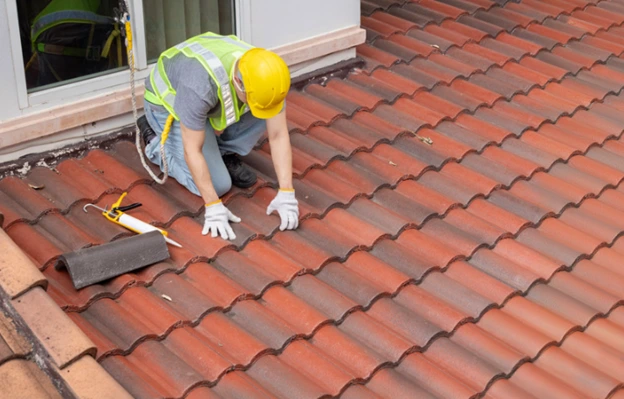 Roofing contractor repairing a tile roof.