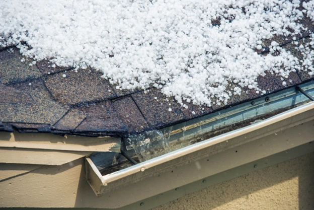 Snow accumulation on a roof near a gutter during winter.