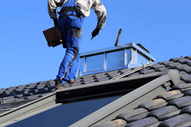 Roofing company contractor inspecting a chimney and skylight on a residential roof.