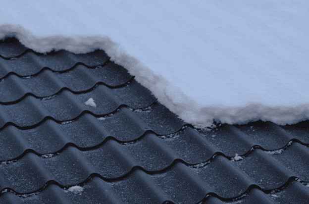 Snow buildup on a black metal roof highlighting winter roofing challenges.