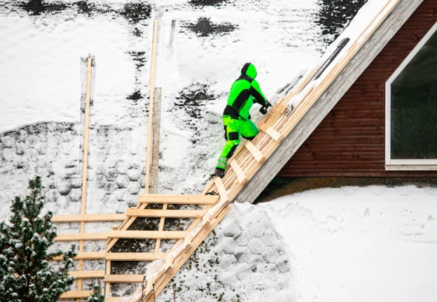 A roofer working on a new roof installation in snowy conditions, showcasing durability and climate readiness.