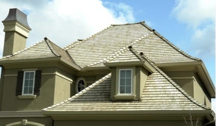 The elegant roof of a luxury stucco home, featuring naturally weathered silver-grey cedar shakes installed by Silverline Roofing Ltd