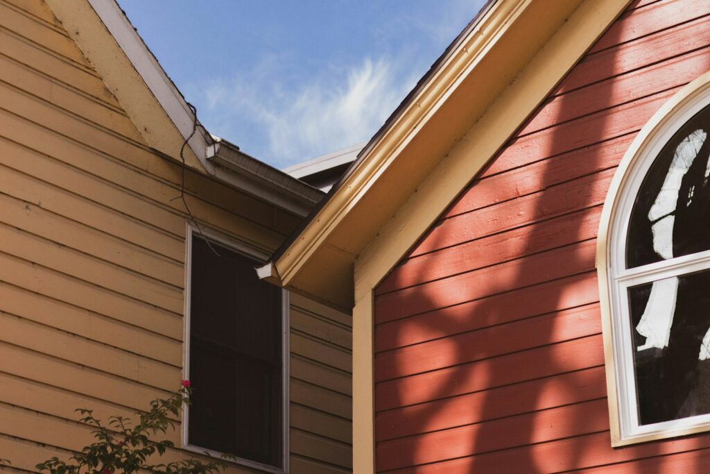 Two-storey house exterior with fresh siding under a clear blue sky
