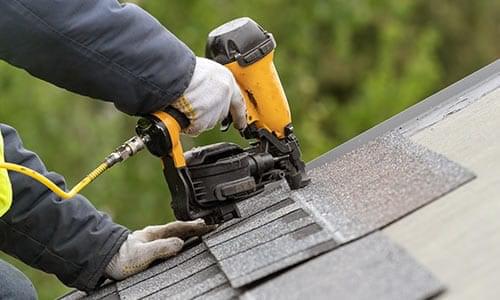 Emergency roof repair Edmonton by Silverline Roofing Limited, showing a technician using a pneumatic nail gun to quickly secure new shingles on a damaged roof.